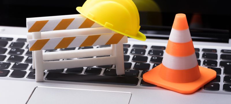 Road,Barrier,With,Hard,Hat,And,Traffic,Cone,On,Laptop